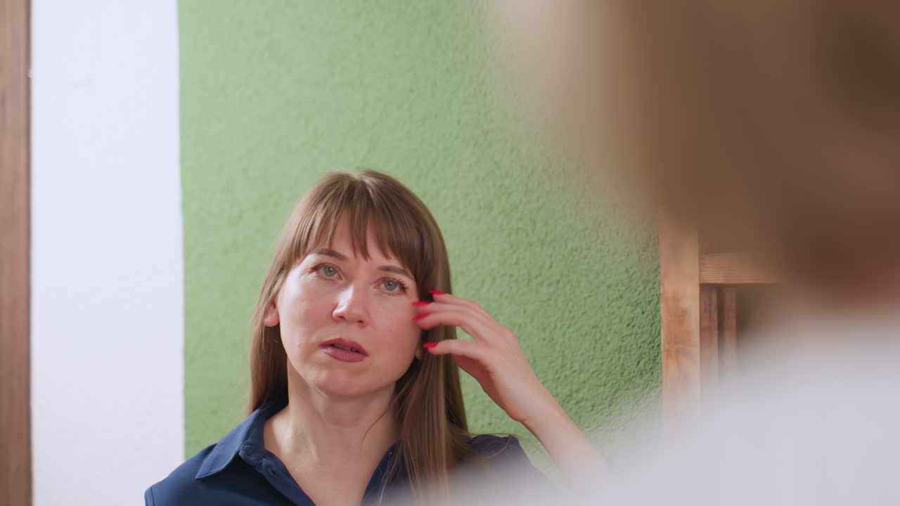 Therapeutic companion with thoughtful expression listens during emotional dialogue in tranquil space with green wall and warm lighting, reflecting compassion and connection in supportive setting