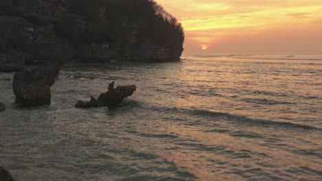 an aerial shot of a blood orange sunset along the balinese coastline
