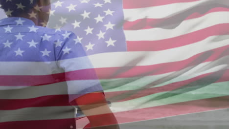 animación de un hombre biracial en silla de ruedas por el mar sobre la bandera de los estados unidos