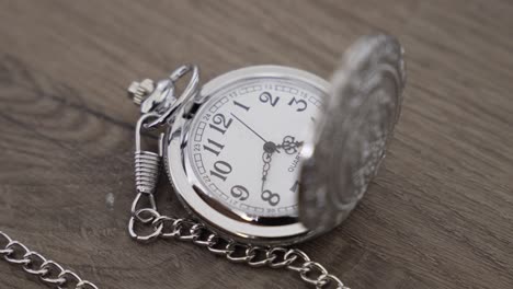 silver pocket watch on wooden surface