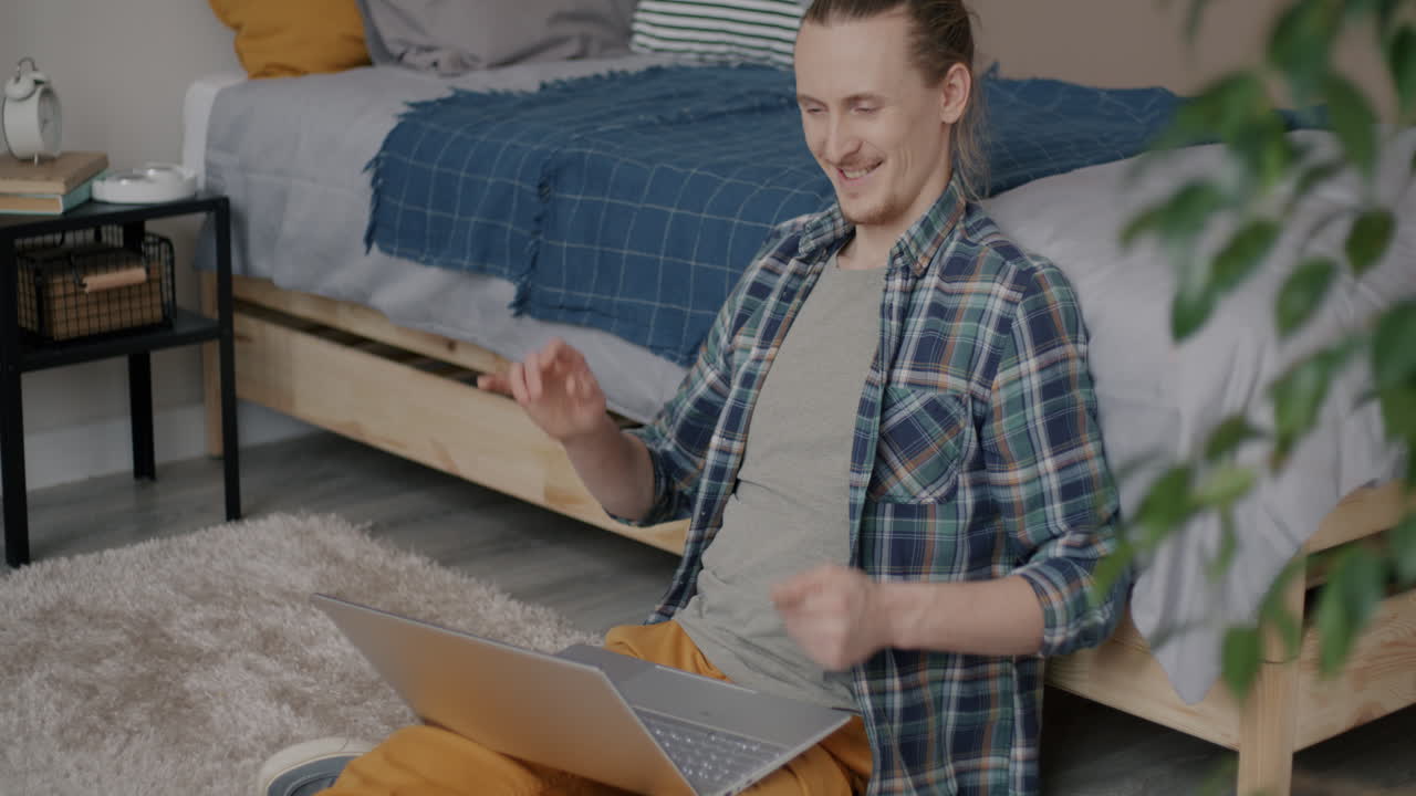 Man shopping online and celebrating purchase in bedroom