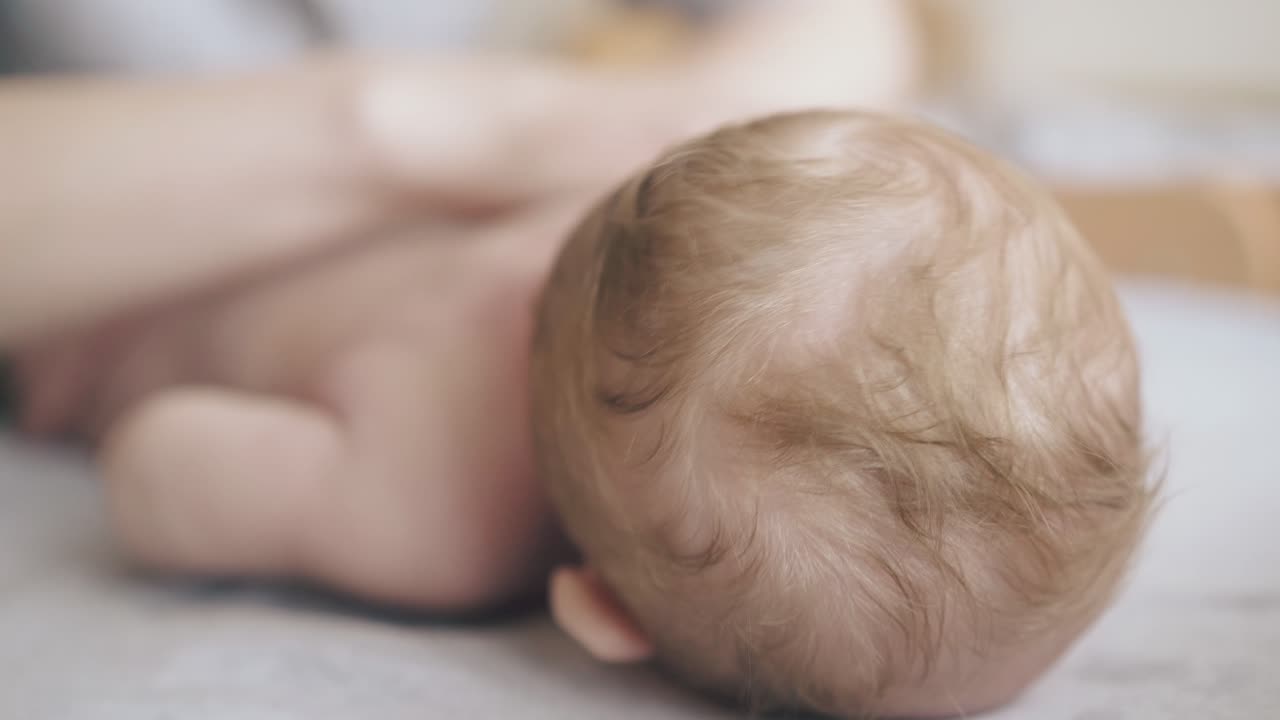 маленький новорожденный мальчик лжет, а педиатр практикует массаж.