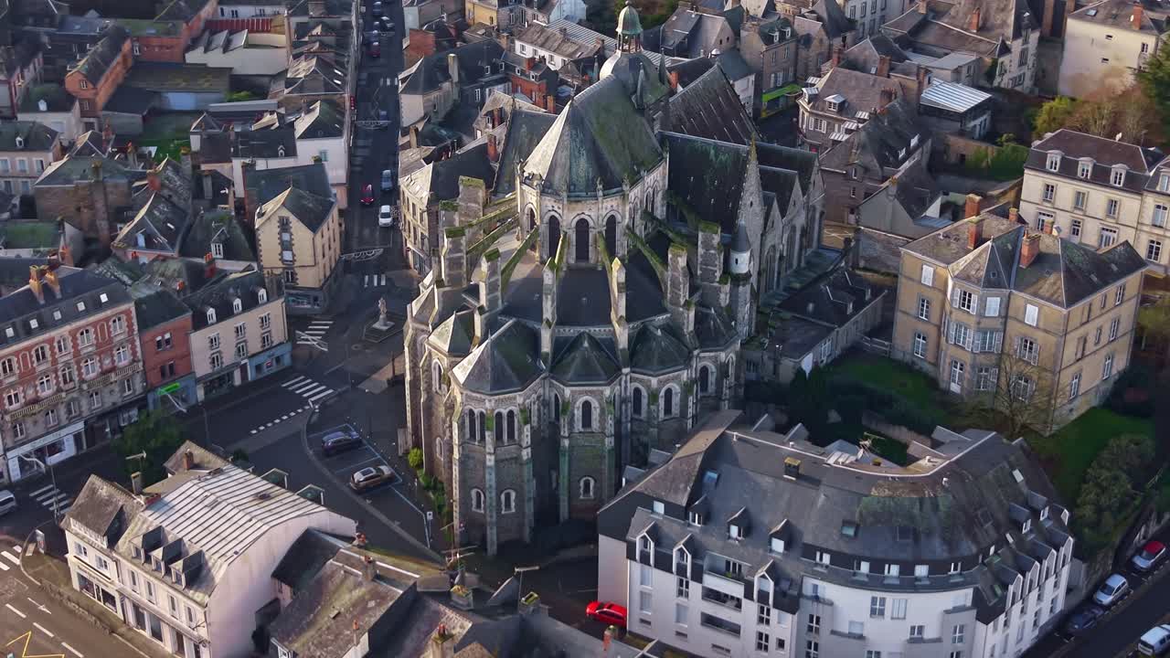 Vista aerea da drone ad alta quota della Basilica di Notre Dame des Miracles, circondata dal centro storico di Mayenne, con architettura gotica in pietra e tetti urbani, regione dei Pays de la Loire, Francia