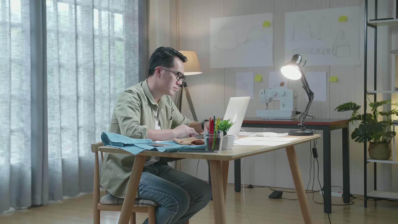 사무실에서 노트북으로 타이핑하는 레이아웃 본드와 직물의 아시아인 디자이너