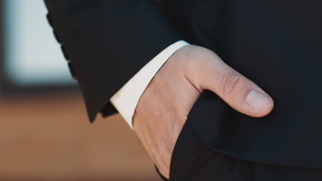 man with gold wedding ring puts hand into trousers pocket