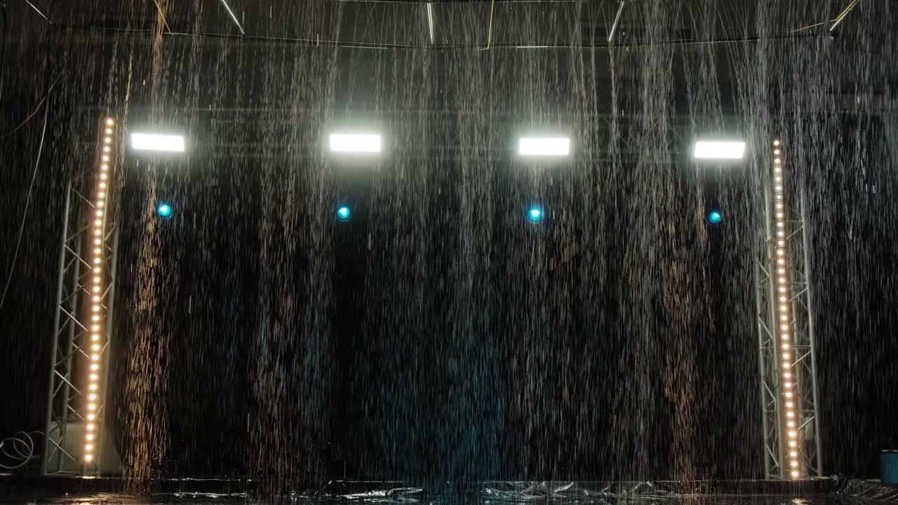 The effect of rain in the aqua studio against the background of spotlights. Water texture. Slow motion