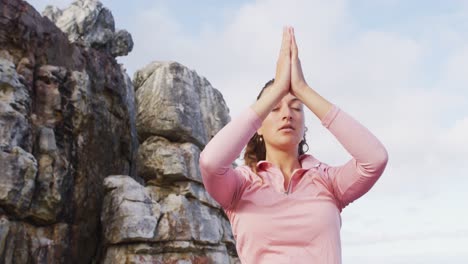 caucasian woman practicing yoga meditation outdoors in rural mountainside setting