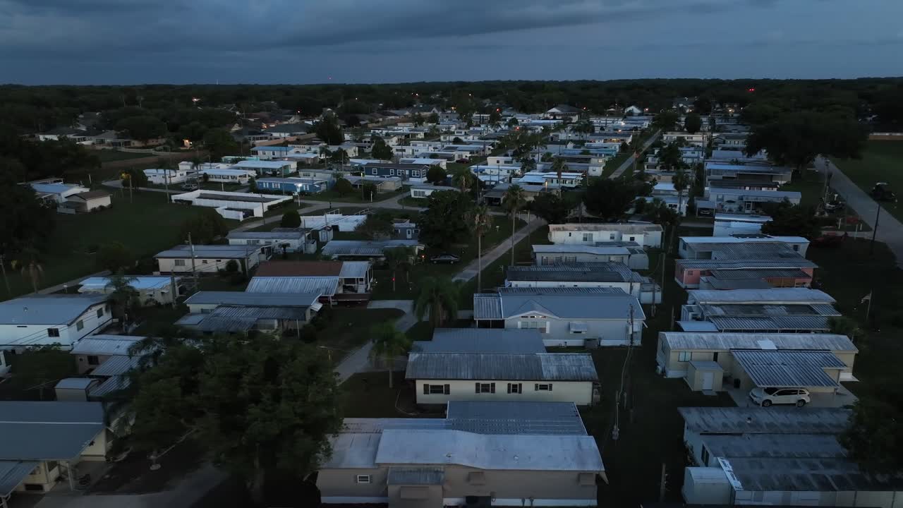 Dusk scene in low class residential area of American town. Aerial wide shot. Mobile trailer homes in social district of plant city, Florida. Rusty roofs of buildings
