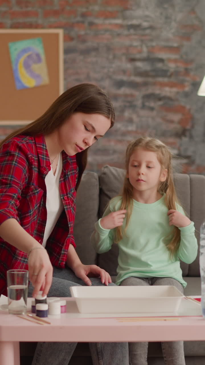hermanas bonitas eligen colores de pintura para el dibujo oriental ebru en la mesa en la sala de estar. educación de arte familiar. pasatiempo creativo y ocio para niños