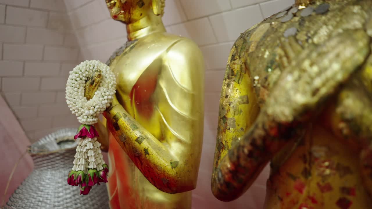Golden Buddha Statues Adorned with Gold Leaf and Flower Offerings