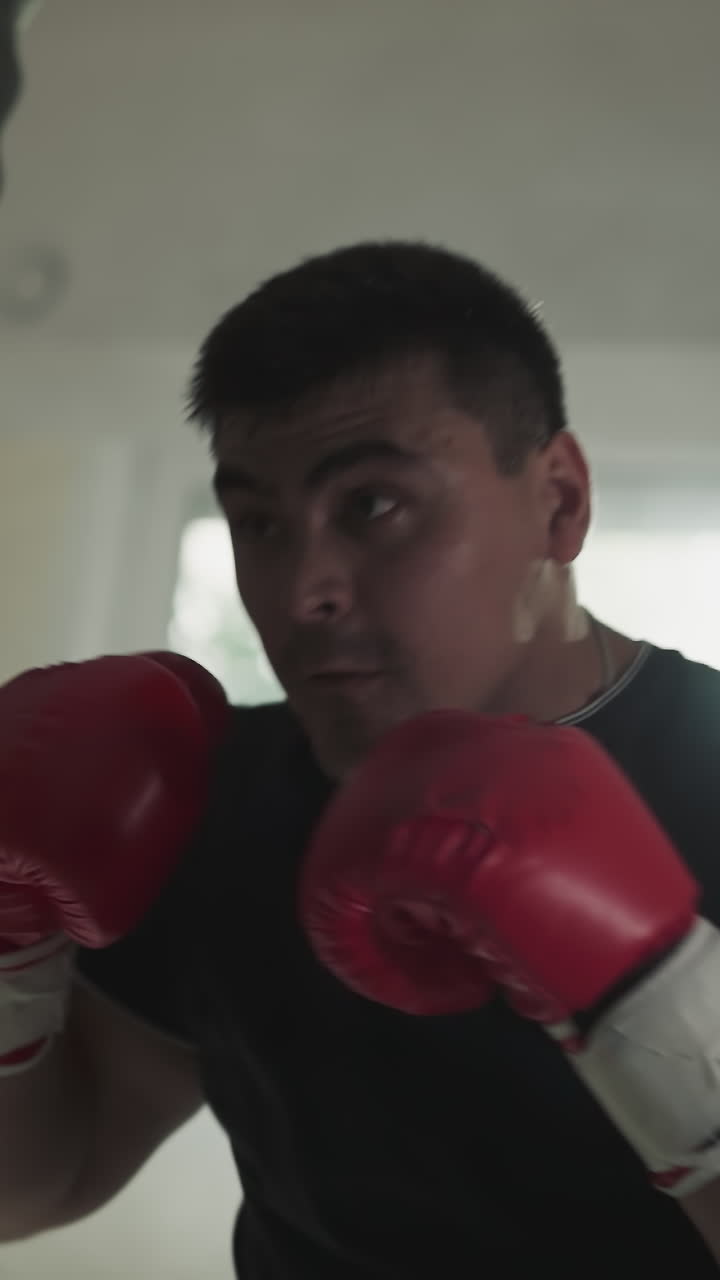 ejercicios de boxeador con saco de boxeo bloqueando la cara en el gimnasio. deportista profesional golpea el equipo contra la ventana en el club de boxeo en cámara lenta. espectáculo de artes de combate