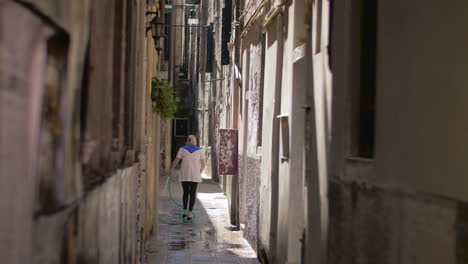 Woman-washing-the-street-with-hose