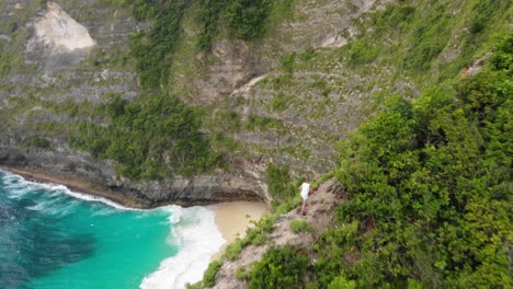 young man hiking on edge of the tropical mountain cliff extreme sport concept