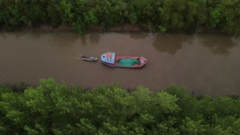 toma lateral cinematográfica de drones de un barco que transportaba un bote pequeño en el río amazonas rodeado de árboles verdes de la selva tropical durante el amanecer