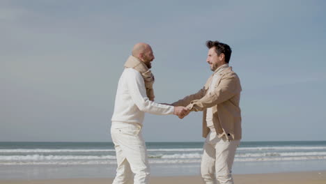 tracking shot of a happy gay couple dancing on the beach 1