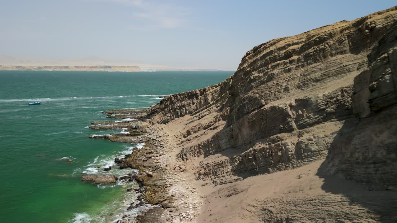 Aerial shot flying close to the layered geological rock formations of the rugged cliffs at Playa La Mina in the Paracas National Reserve Peru