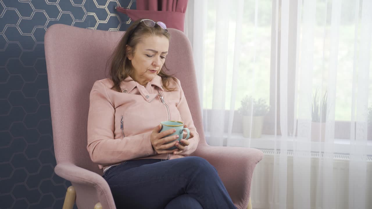 창문 앞에서 뜨거운 음료를 마시는 여자는  ⁇ 집을 만집니다.