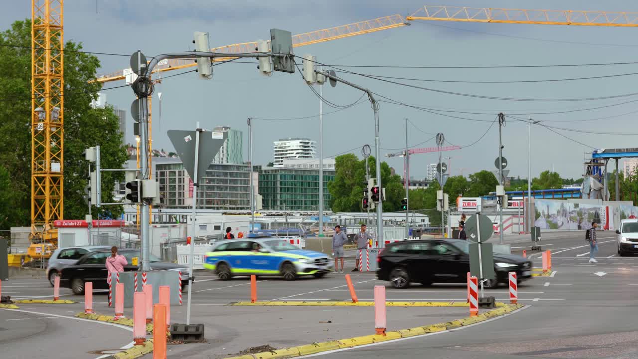 Busy intersection with cars and people obstructed by construction work