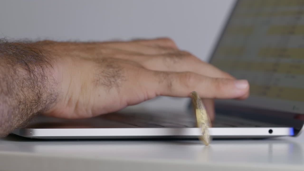 la mano de un hombre escribiendo en una laptop con
