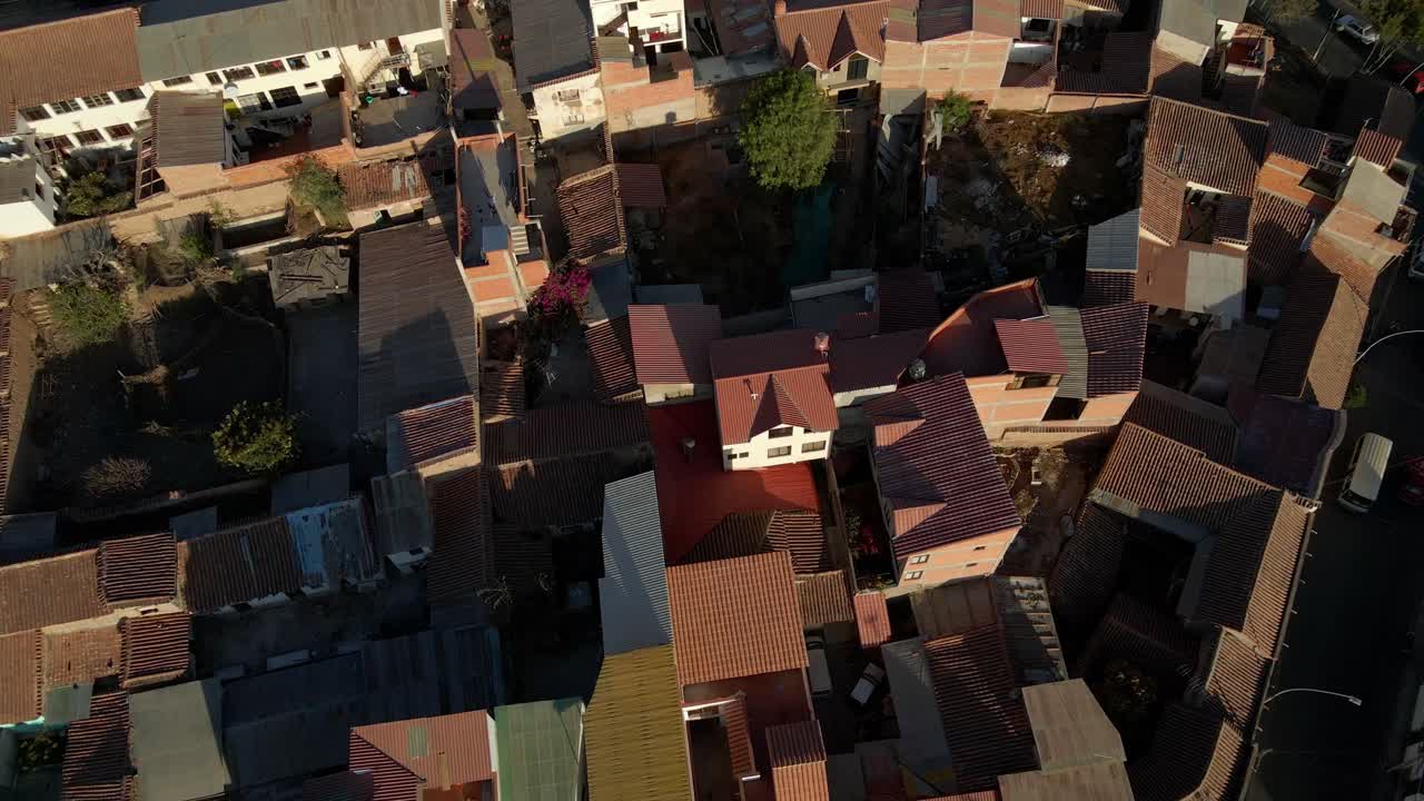 Drone descends over Sucre cityscape in evening light, with grid streets and rooftops visible