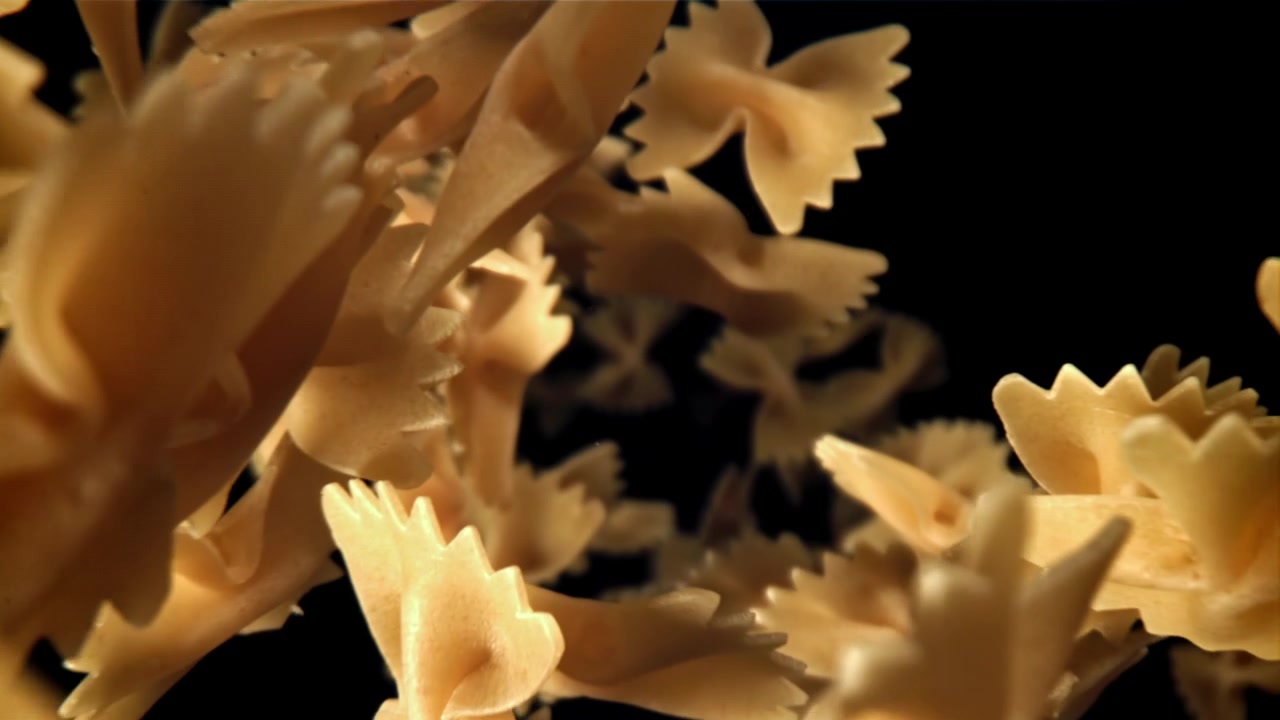 Movimento rallentato di pasta farfalle che cade su uno sfondo scuro