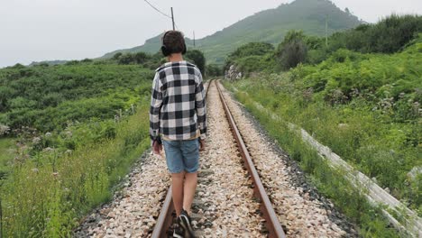 boy walking on train tracks