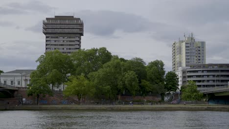 urban view of modern architecture along the river in frankfurt with green trees
