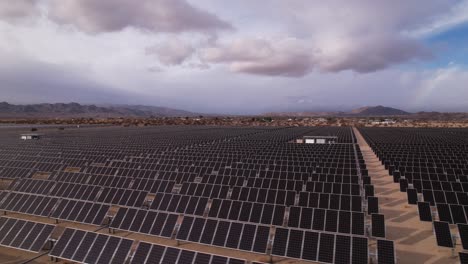 Drohnenaufnahmen-Aus-Der-Luft-Eines-Solarfeldes-Im-Joshua-Tree-Nationalpark-An-Einem-Sonnigen-Tag-Mit-Regenbogen-Im-Hintergrund,-Schneller-Horizontaler-Schwenk