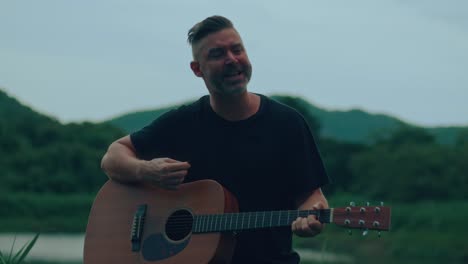 man playing acoustic guitar outdoors