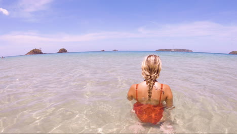 Young-Beautiful-Woman-sits-in-the-crystal-clear-oceans-of-Nacpan-Beach-in-El-Nido-Philippines,-perfect-holiday-and-dream-destination-1