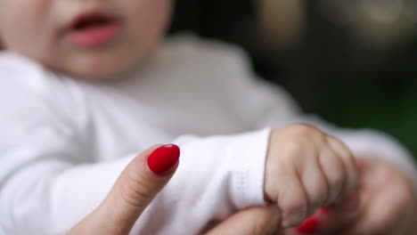 caring mother with baby, concept of love and family. hands of mother and baby closeup, hand in hand. mother care. playing with baby at home. slow motion