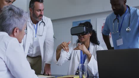 doctora asiática en la mesa usando auriculares vr con un grupo diverso de colegas reunidos a su alrededor
