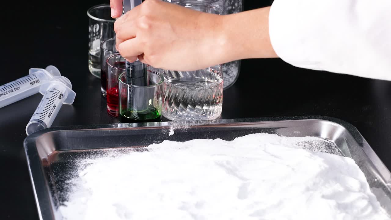 손은 베이킹 소다와 함께 다채로운 액체를 혼합합니다.