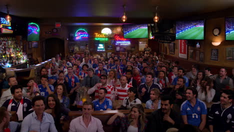 crowd celebrating a soccer game at a pub