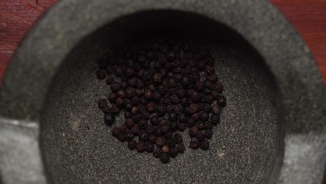 peppercorns falling into granite mortar