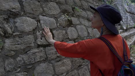 primer plano de una mujer tocando las piedras en la acrópolis en el parque arqueológico ek balam en yucatán, méxico