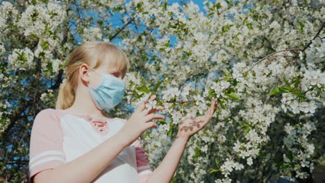 un niño triste con una máscara está admirando los problemas de alergia de un árbol en flor