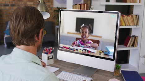 Caucasian-male-teacher-sitting-at-desk-using-computer-having-online-school-lesson