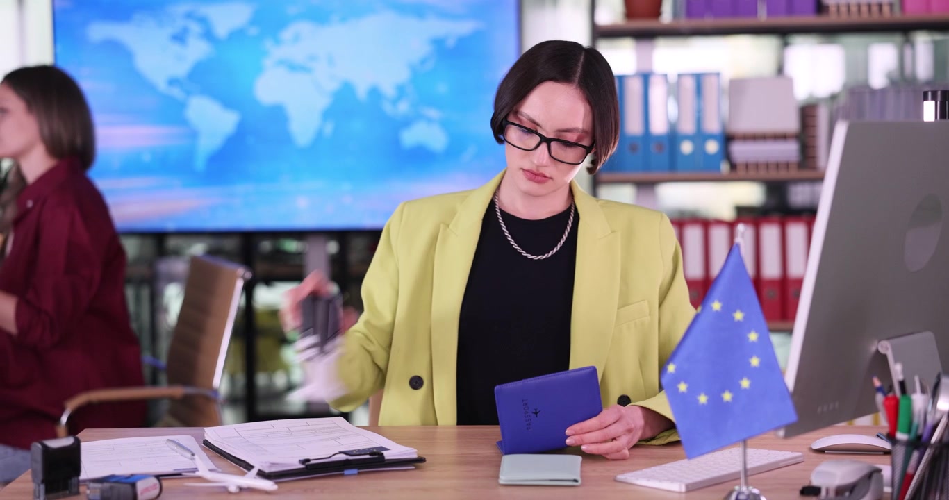 Zaměstnanec ambasády vkládá imigrační razítka do pasů.