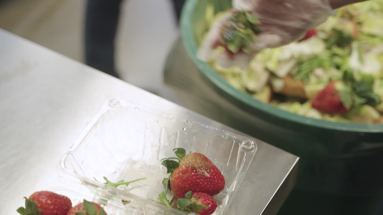 Throwing away moldy strawberries into bin.