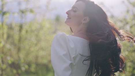 happy-yougn-woman-with-loose-dark-hair-is-walking-in-blooming-in-orchard-in-spring-day