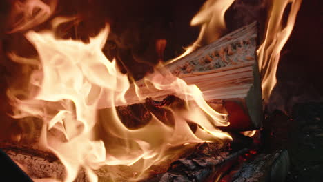 slow motion footage of flames surrounding a red hot wooden log burning in a camp fire pit