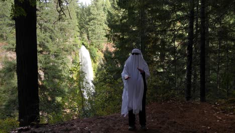 una persona vestida de fantasma baila frente a una gran cascada