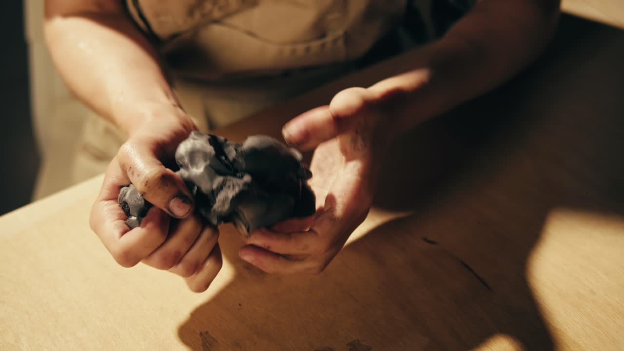 Hands working with dark clay