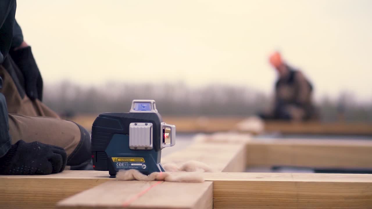 지붕 프레임 프로젝트에서 레이저 레벨을 사용하는 건설 노동자