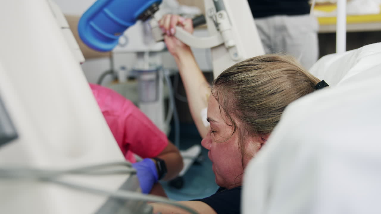 Woman trying hard pushing a baby at labor. Child delivery in modern hospital.