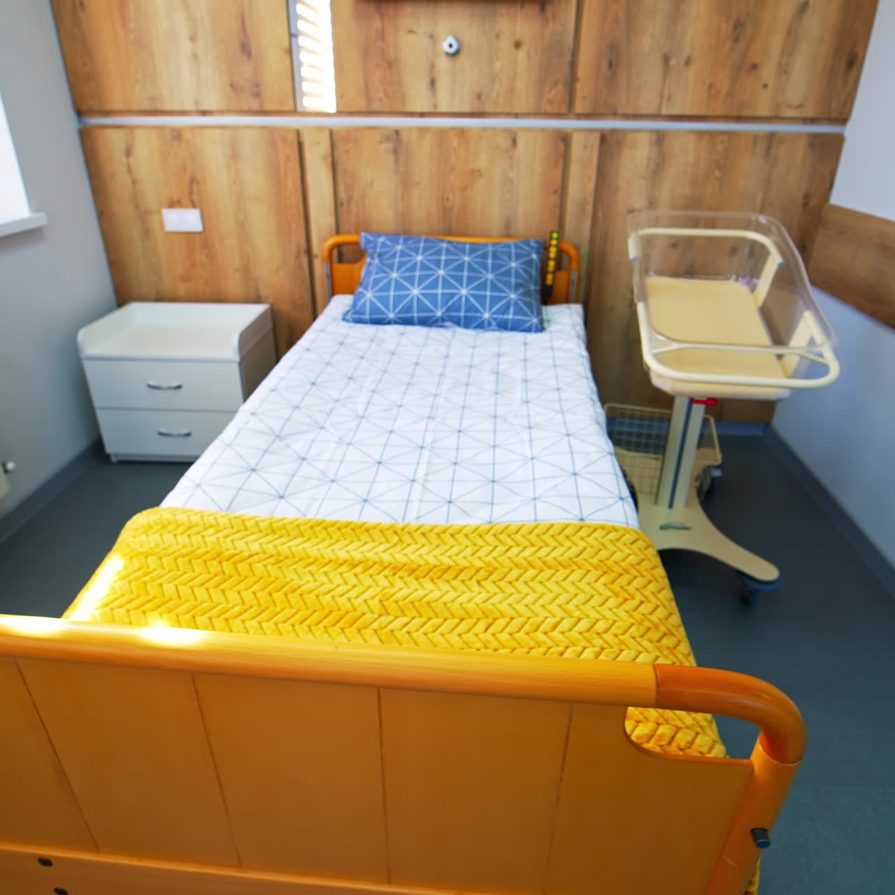 Comfortable bed for mothers who gave birth recently. Little plastic transparent baby crib for newly born child beside mother's bed