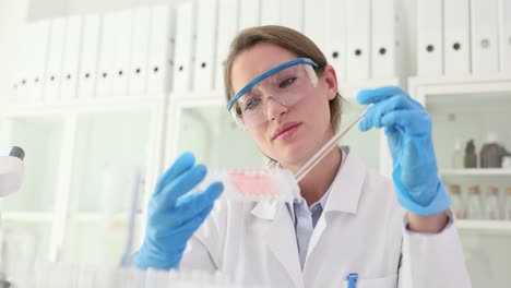 a female scientist in a lab coat and safety glasses working with samples in a laboratory