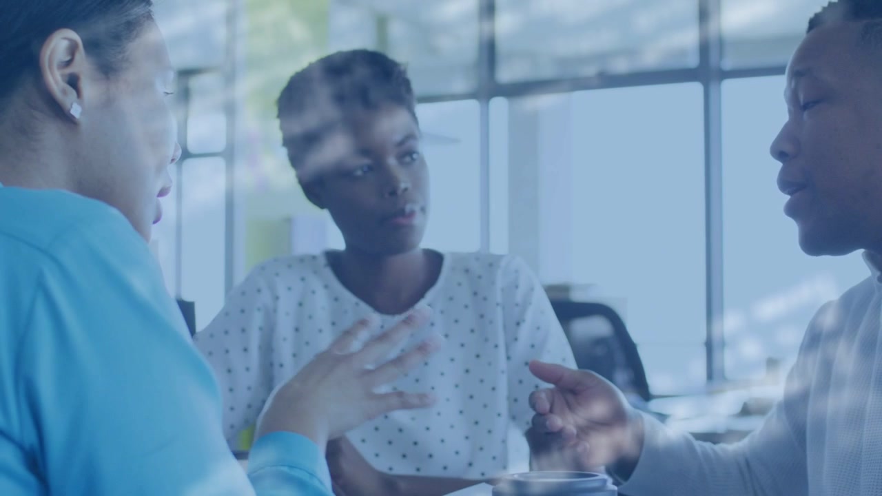 Right woman starting UX review pointing mockups as moving overlay crossing group, center responding