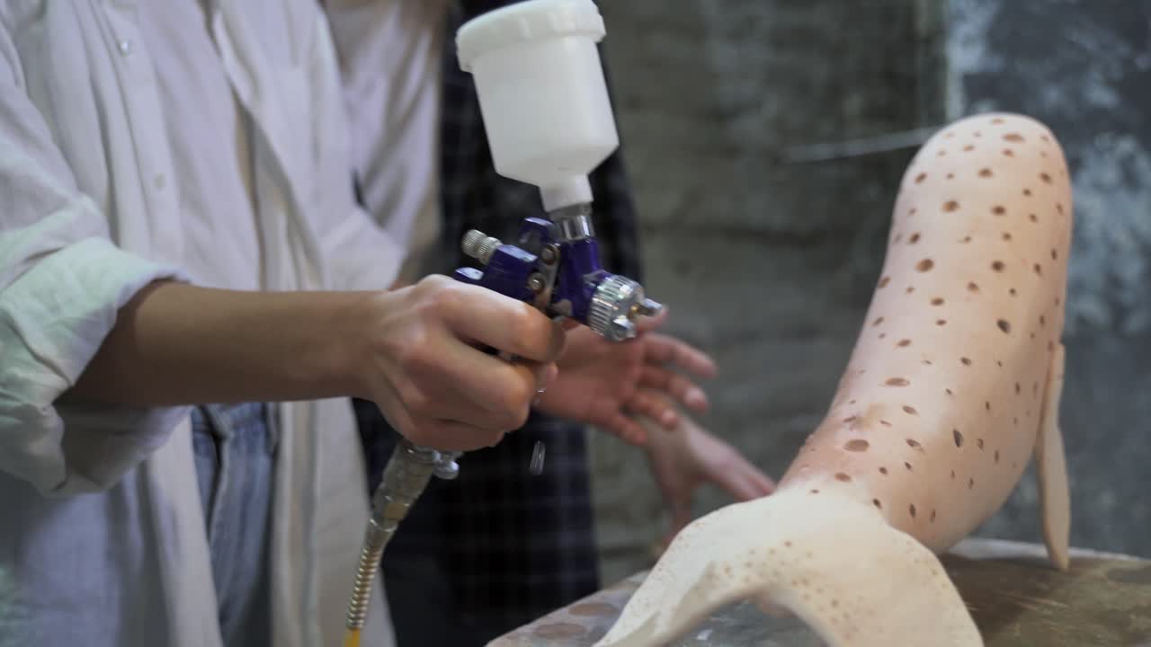 pintando con spray una pierna de escultura